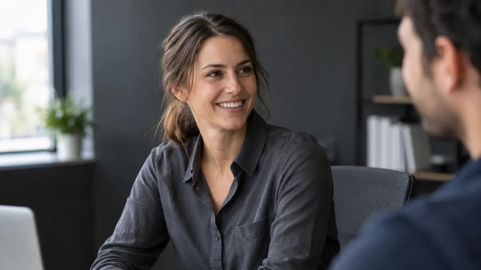A hiring professional turns toward a colleague with a warm smile.