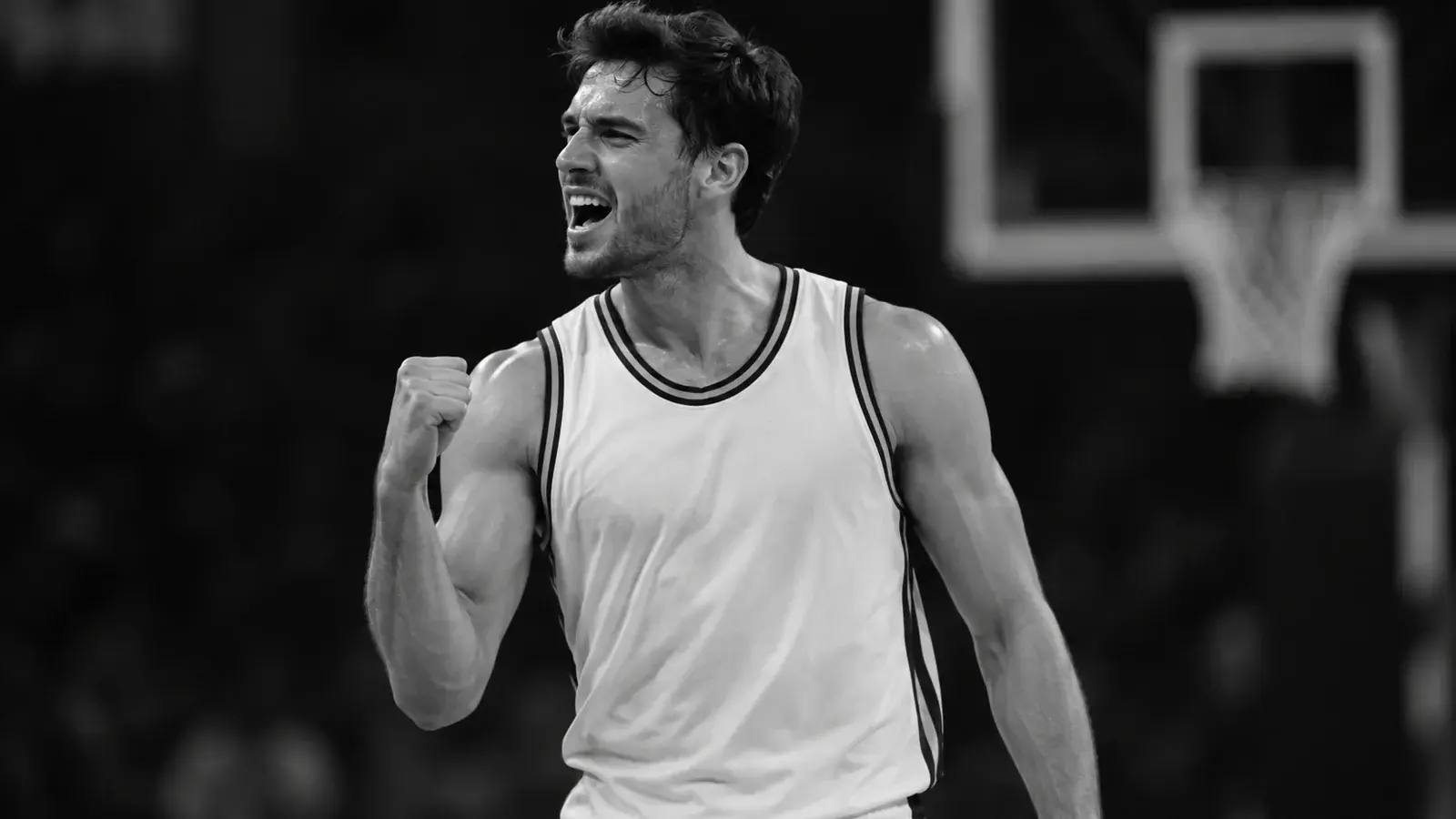 A basketball player celebrates a successful play in a black-and-white photograph.