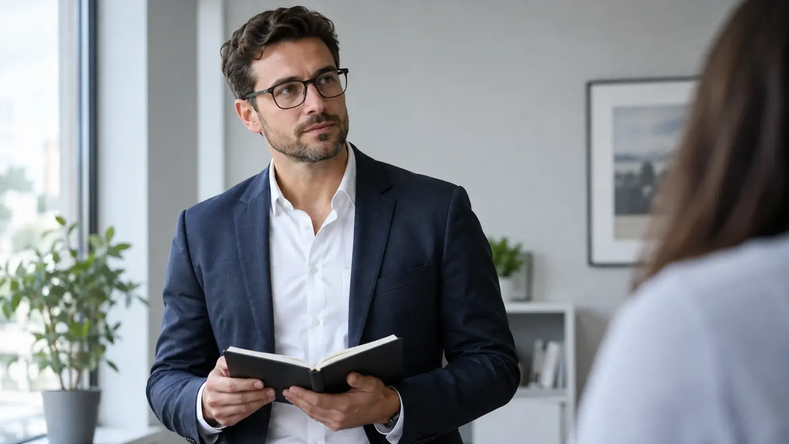 A sales coach reviews a notebook while listening to a colleague.