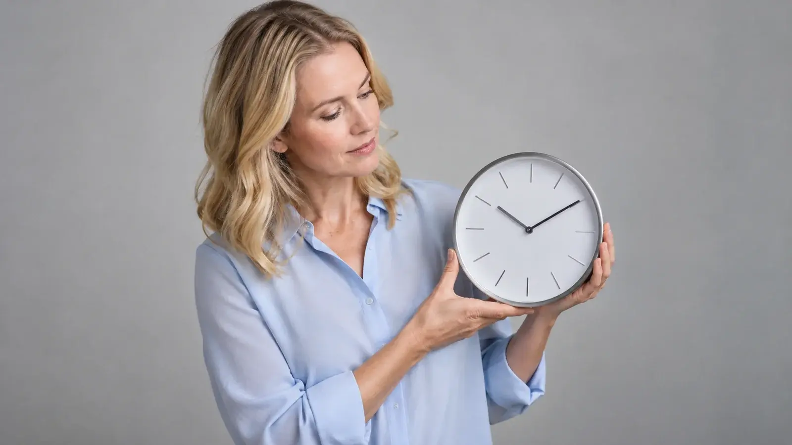 A woman checks a round analog clock with simple hour markers.