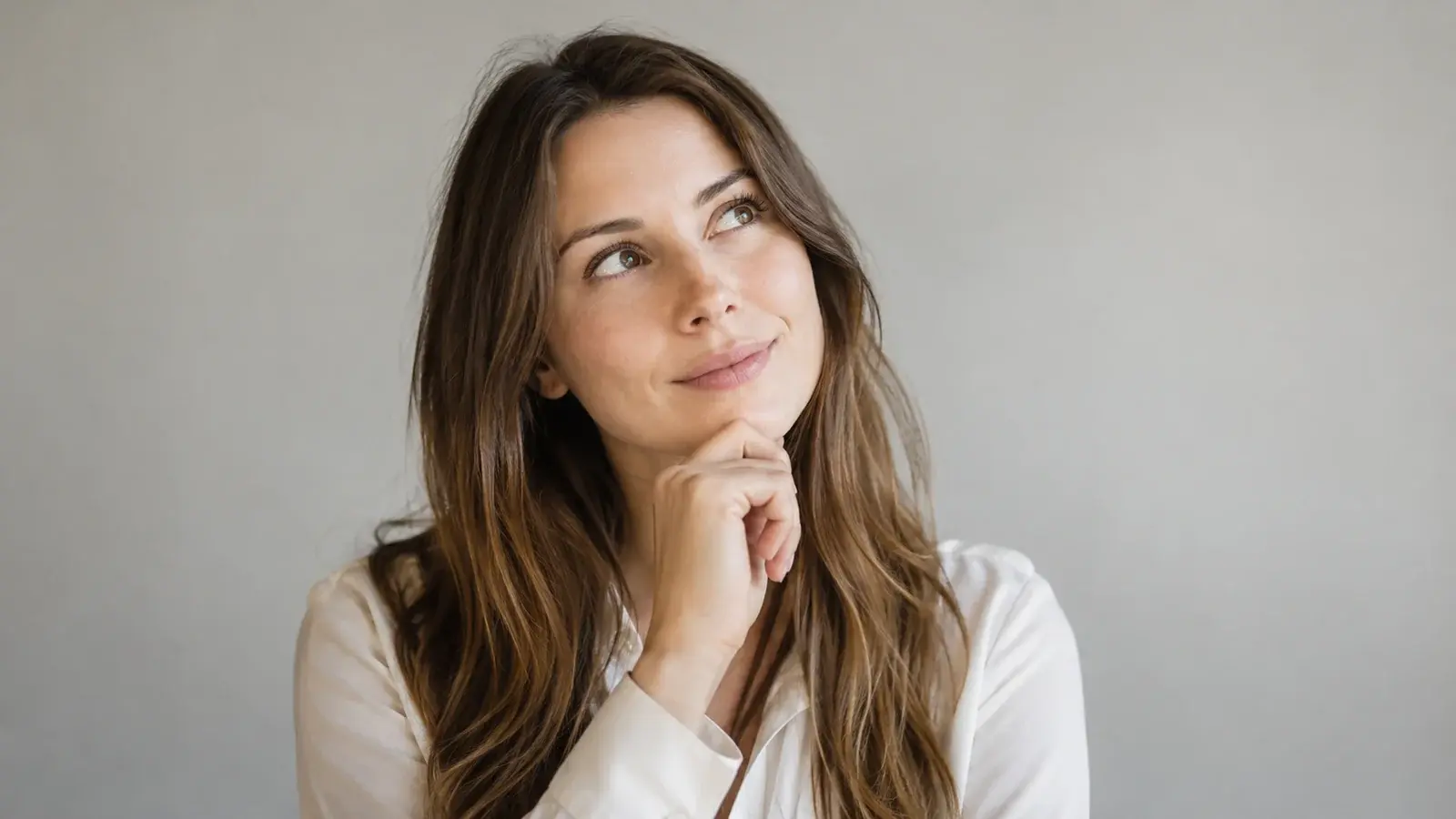 A woman looks upward thoughtfully while considering a question.