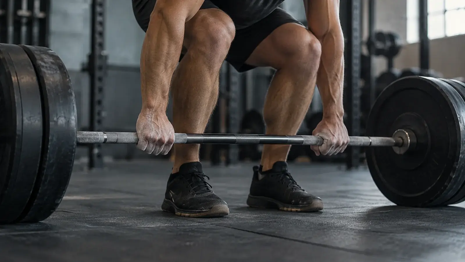 An athlete grips a barbell while preparing for a lift.