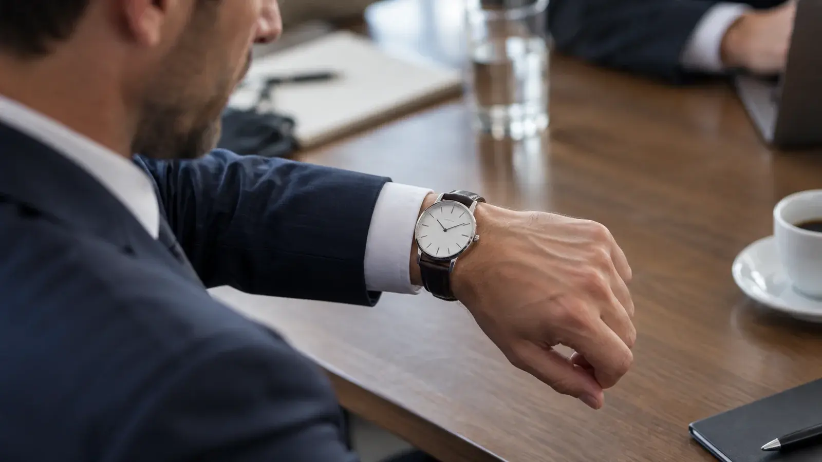 A professional checks a wristwatch during a meeting.