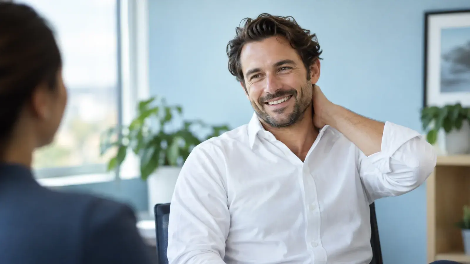 A professional in a white shirt smiles during a conversation.