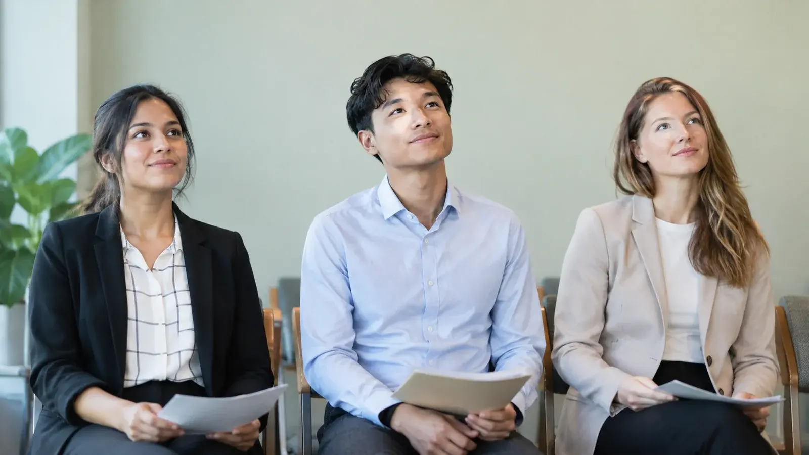 Three candidates look up as an interviewer approaches.